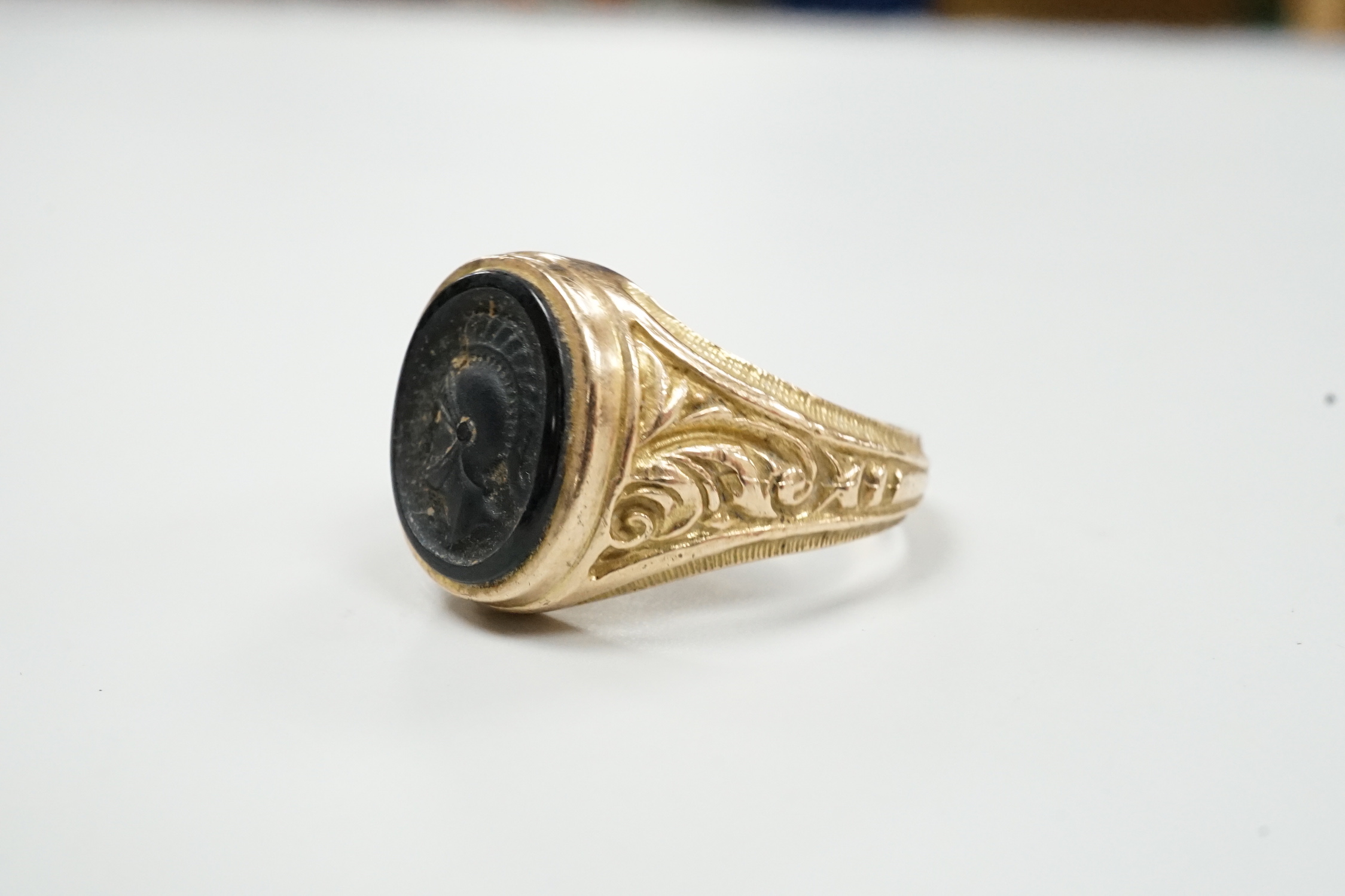 A 1970's 9ct gold and black onyx? set signet ring, carved with the bust of a Roman soldier, size T, gross weight 8 grams.